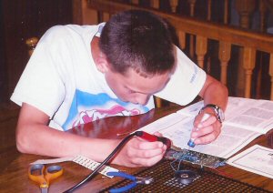 William solders a siren assembly.